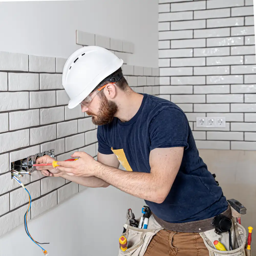 Electrician repairing home electrical outlet with screwdriver
