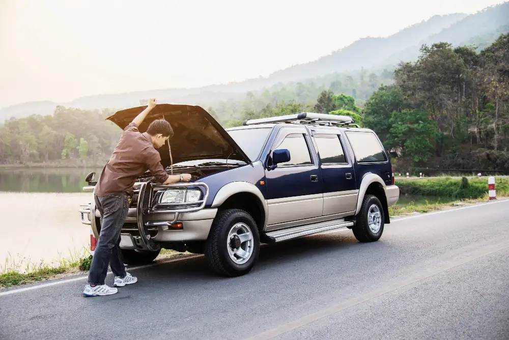 Man on the road with a broken car waiting for a towing service